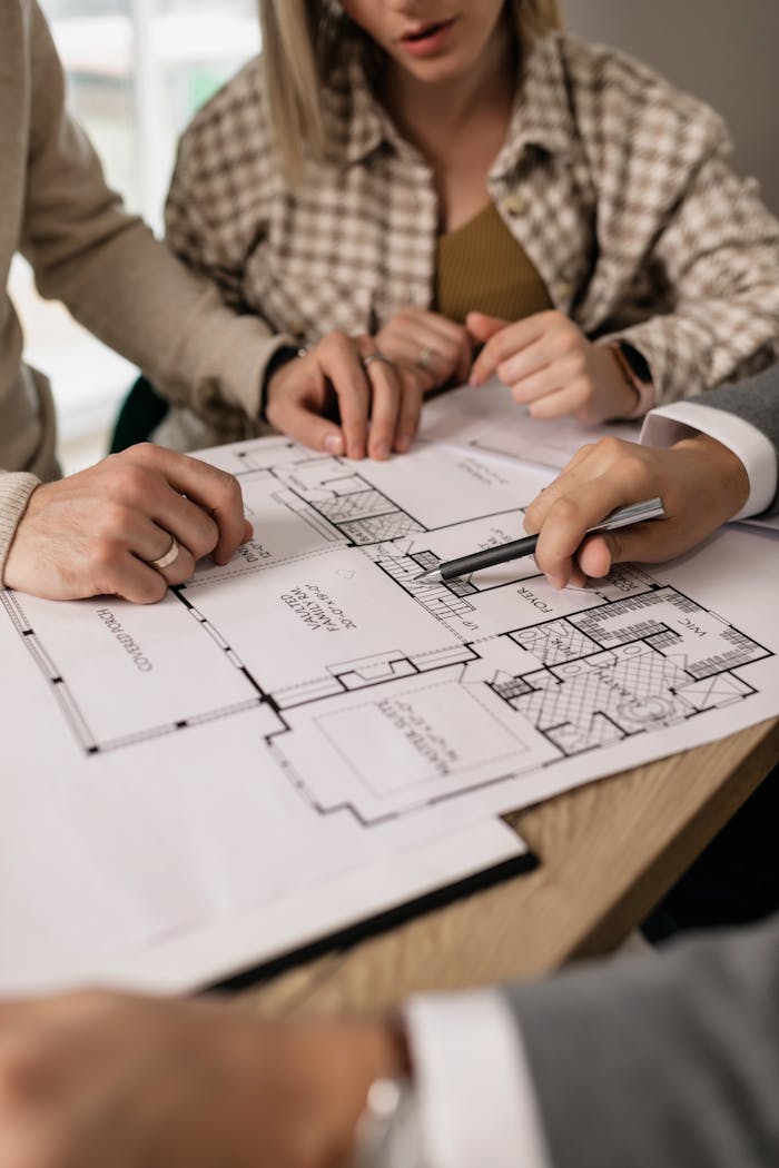 about-01 People discuss architectural plans in a real estate planning session, highlighting teamwork.