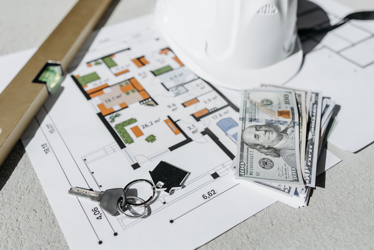 our-experience Floor plan with cash, keys, and hard hat symbolizing real estate investment and property planning.