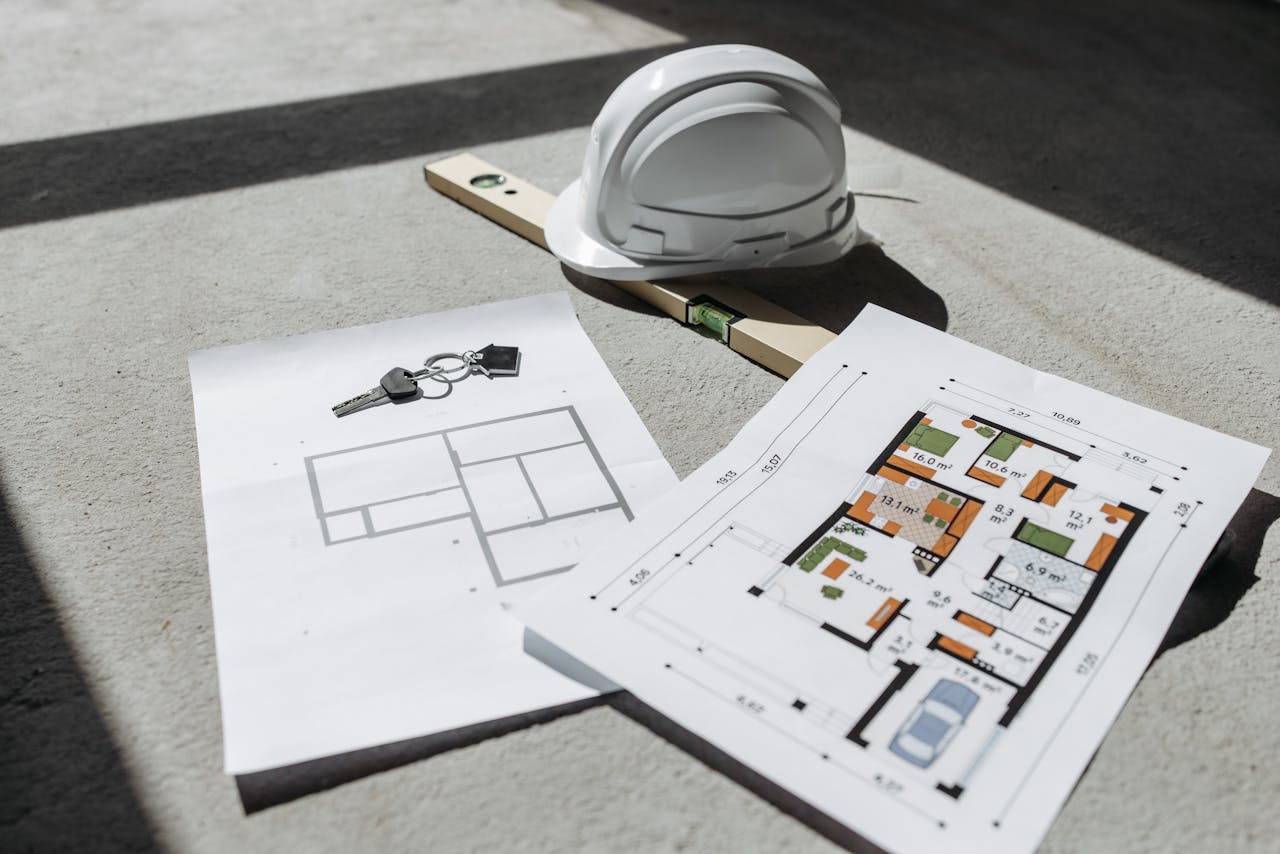 services-03 Architectural floor plans with helmet and keys on sunlit floor, perfect for real estate or construction themes.